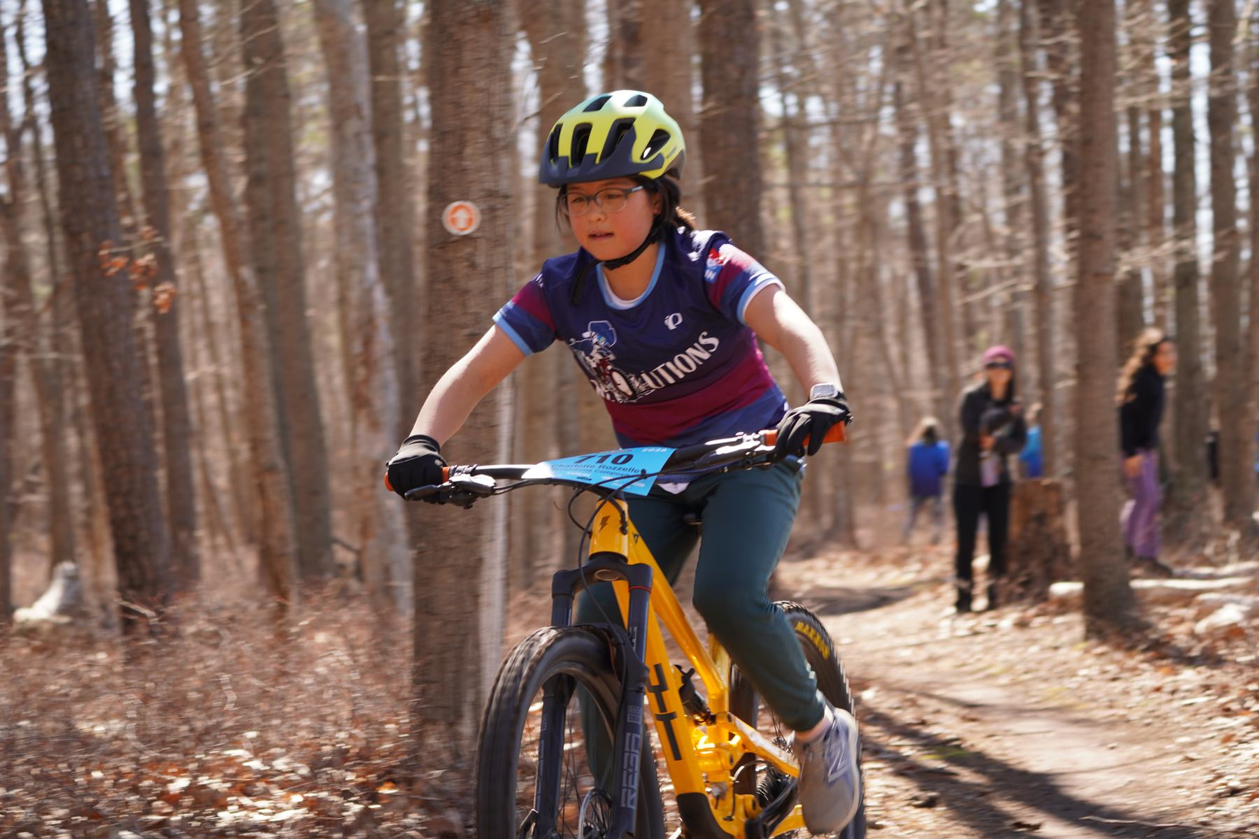 Rider on a yellow bike coming through the pines